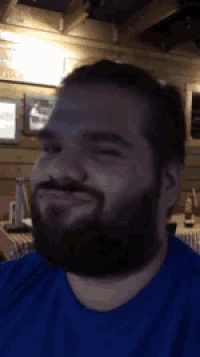 a man with a beard wearing a blue shirt is smiling