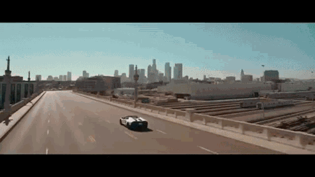 a car is driving down an empty highway with a city skyline in the background .