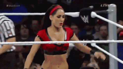 a woman is standing in a wrestling ring with a referee behind her .