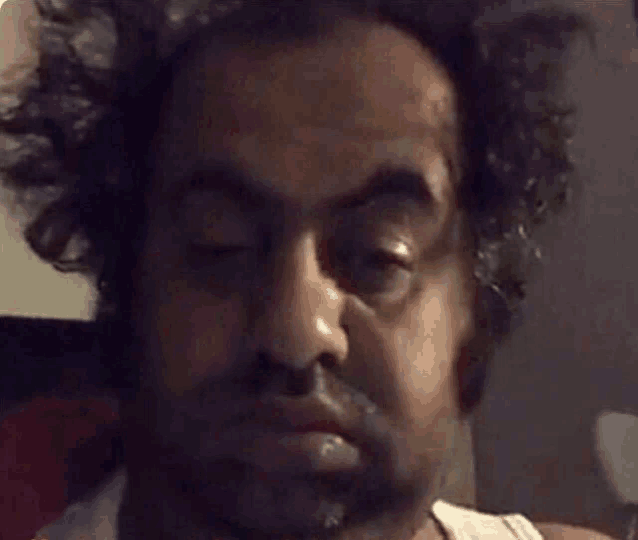 a man with curly hair and a beard is making a funny face .