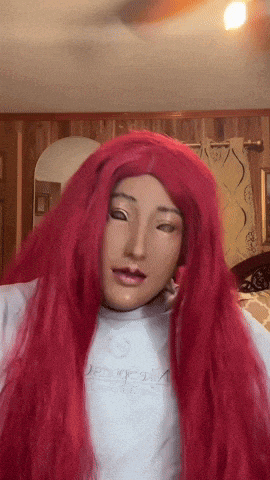 a woman wearing a mask and red hair is wearing a white shirt that says ' duck ' on it