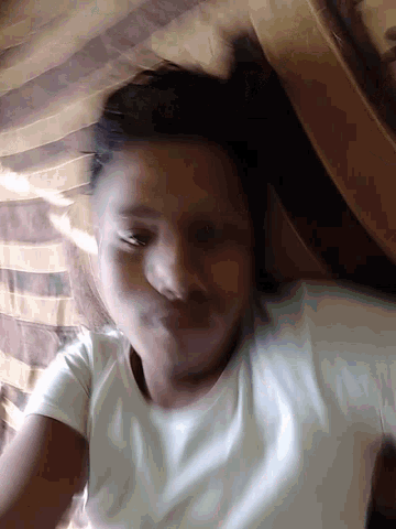 a man in a white shirt is laying on a bed with a striped blanket