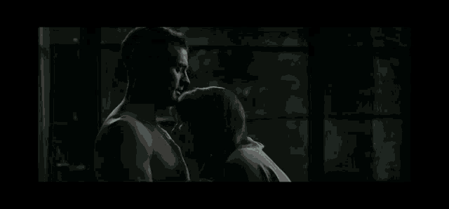 a man and woman kissing in front of a window in a dark room