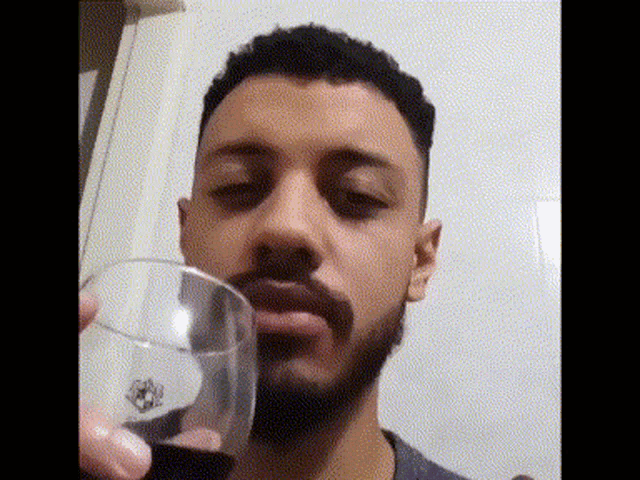 a man with a beard is holding a glass of wine in his hand .