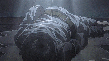 a man in a striped shirt is laying on the ground in a dark room