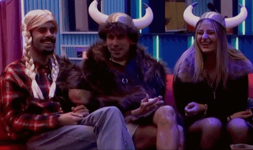 a man wearing a horned helmet sits next to two other people