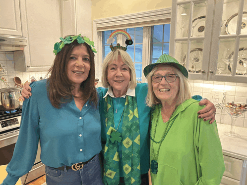 three women are posing for a picture in a kitchen and one has a gucci belt