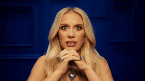 a blonde woman with blue nail polish and a heart shaped necklace