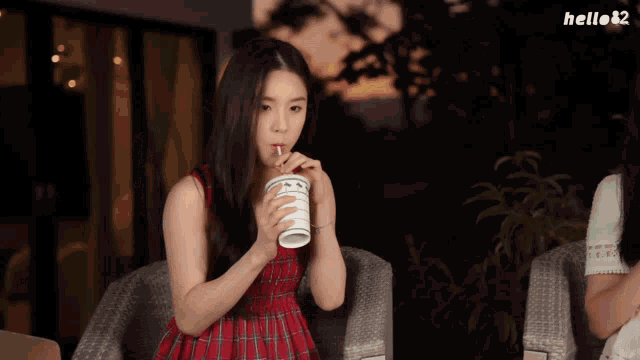 a girl in a red dress is holding a cup with a straw in her hand and asking yeji how is it