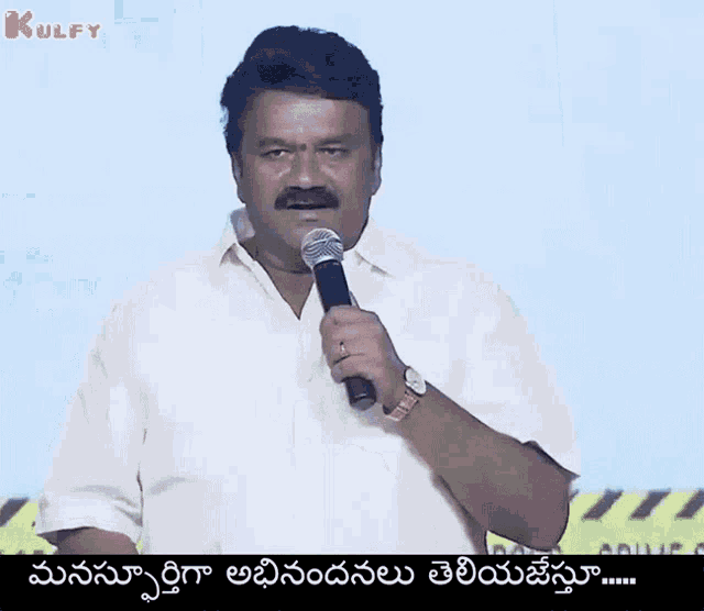 a man in a white shirt is holding a microphone and speaking in a foreign language ..