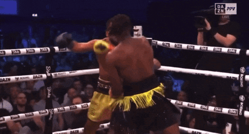 two boxers are fighting in a boxing ring and one of them is wearing yellow shorts with fourn on them