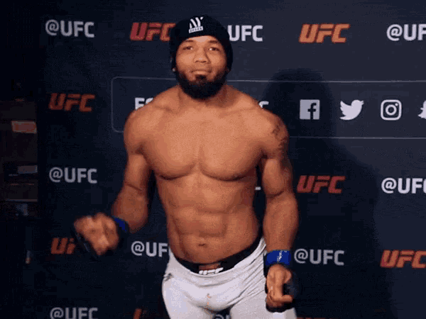 a man without a shirt is standing in front of a ufc wall