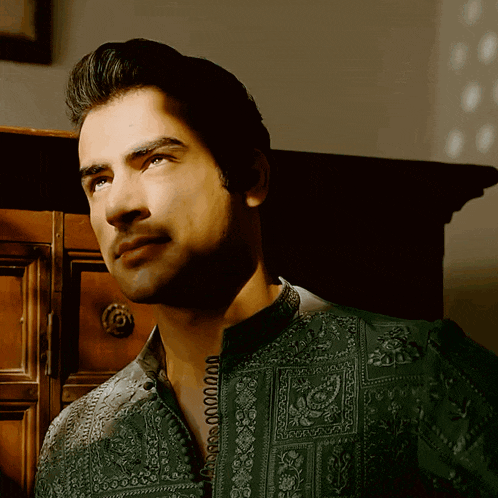 a man is wearing a green shirt with a pattern on it