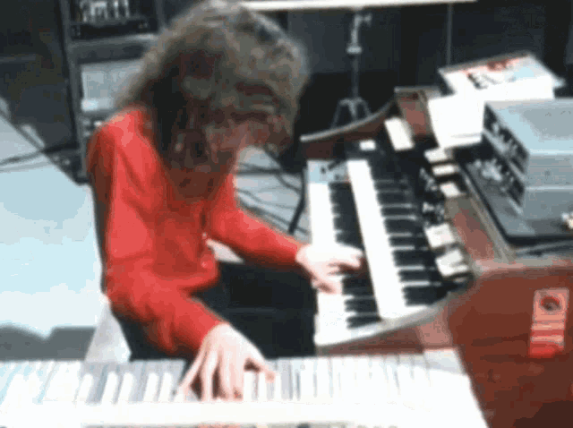 a person in a red shirt is playing a piano