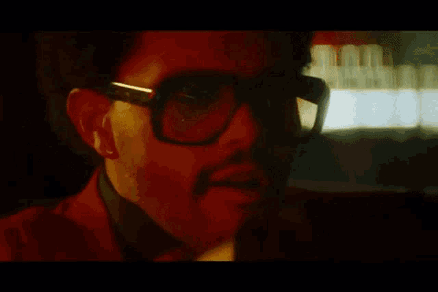 a close up of a man wearing red sunglasses and a red jacket .