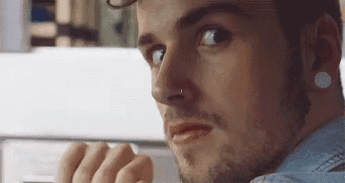 a close up of a man 's face with a nose ring and ear plugs .