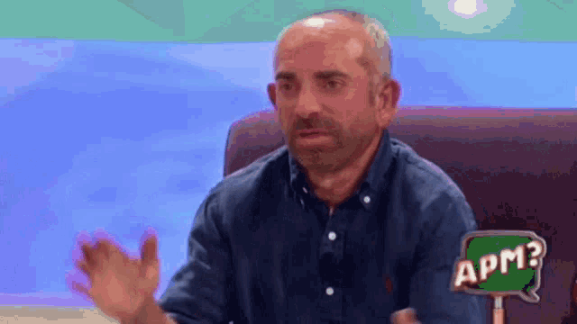 a man with a beard is sitting in front of a sign that says apm