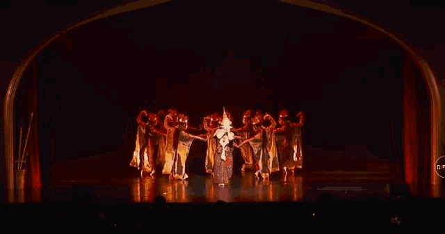 a group of people are dancing on a stage with a circle around them that says nr on it