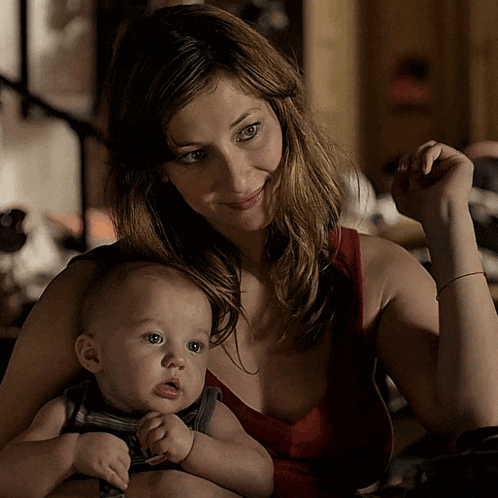 a woman is holding a baby in her arms and smiling