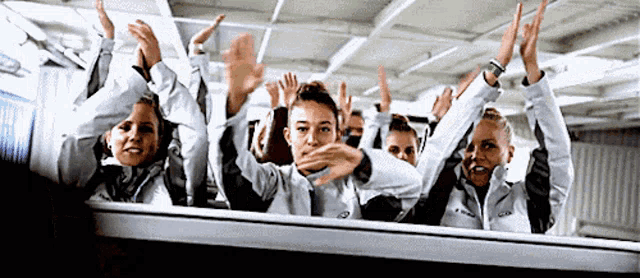 a group of people are raising their hands in the air