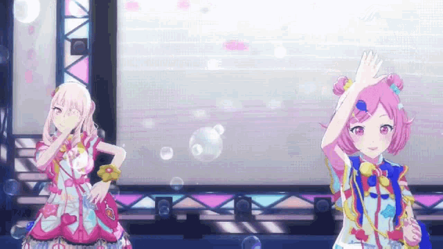 two anime girls are dancing on a stage with soap bubbles .