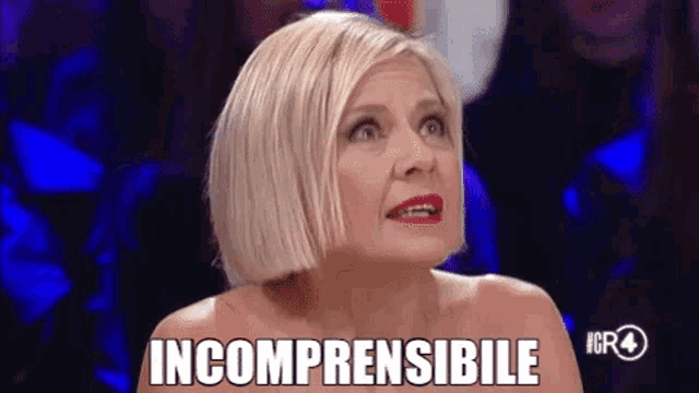 a woman with blonde hair and red lipstick is sitting in front of a crowd and says incomprensibile