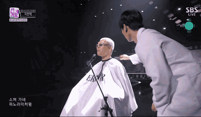 a man in a white cape with error written on it stands in front of a microphone