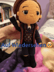 a person is holding a crocheted doll with auf wiedersehen written on it