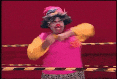 a clown in a pink and yellow outfit is standing in front of a yellow and black tape barrier