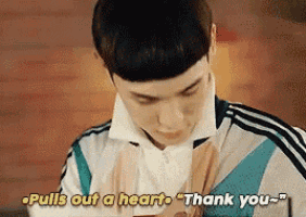 a young man is holding a cell phone in his hand and saying `` pulls out a heart thank you '' .