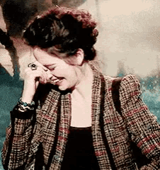 a woman wearing a plaid jacket is laughing