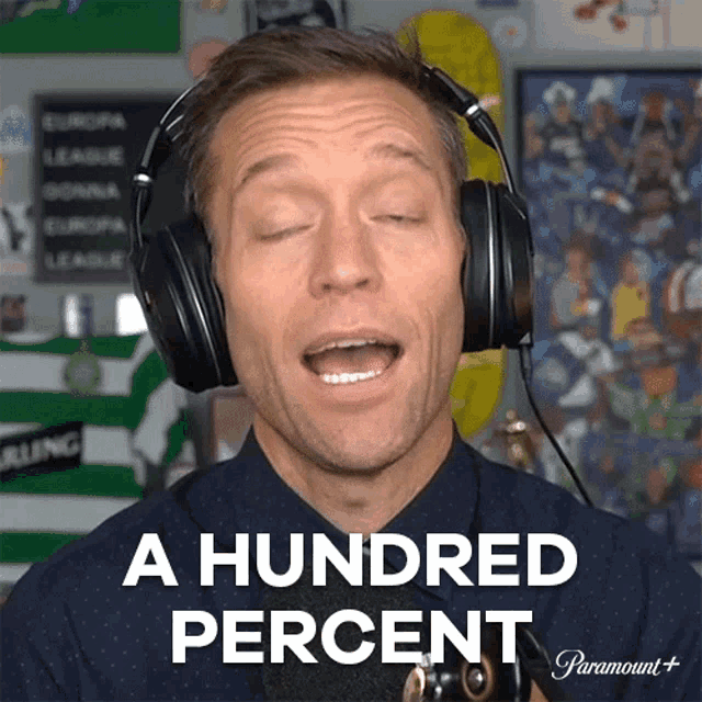 a man wearing headphones says a hundred percent in front of a microphone