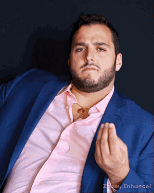 a man wearing a blue suit and a pink shirt has zoom enhance written on the bottom