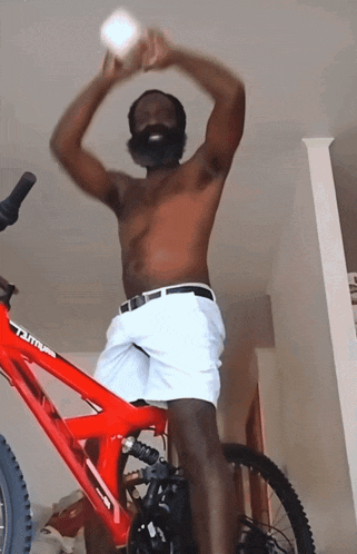 a shirtless man is standing on a red bicycle with the word tutto on the front