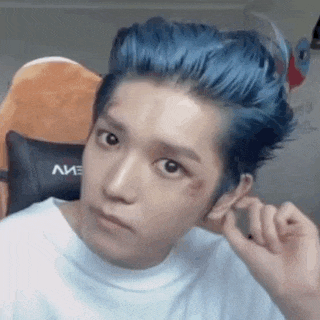 a young man with blue hair is wearing a white shirt and has a bruise on his face .