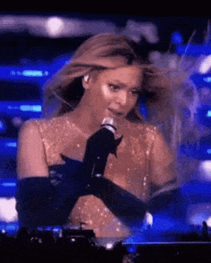 a woman is singing into a microphone on stage .