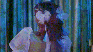 a woman with red hair is wearing a white dress and a blue bow in her hair .