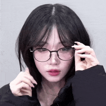 a woman wearing glasses looks at the camera with a sad look on her face