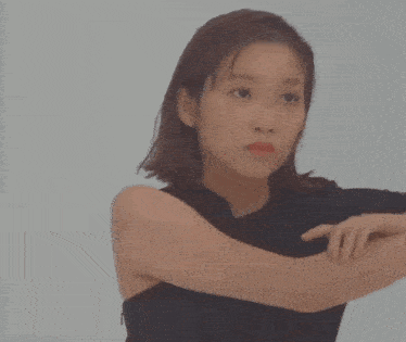 a woman in a black tank top stretches her arm