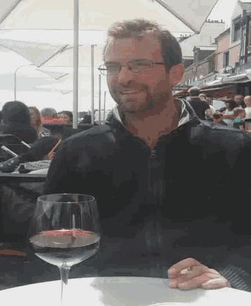 a man sitting at a table holding a glass of wine