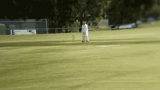 a man playing a game of cricket on a field with a sign in the background that says ' cricket '