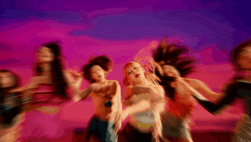 a blurry picture of a group of women dancing in front of a pink and purple background .