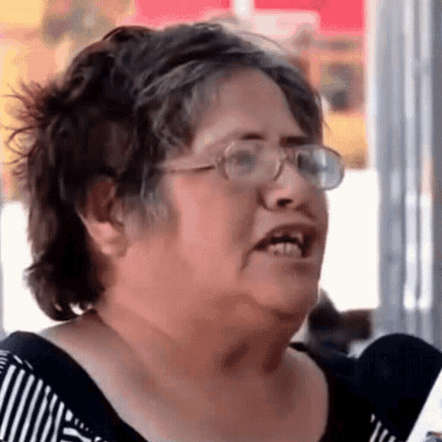 a woman wearing glasses and a black and white striped shirt is making a funny face .