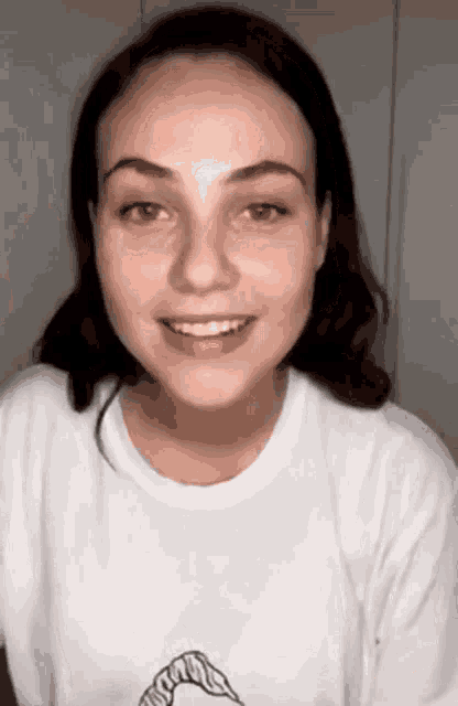 a woman wearing a white shirt with a picture of a shark on it is smiling