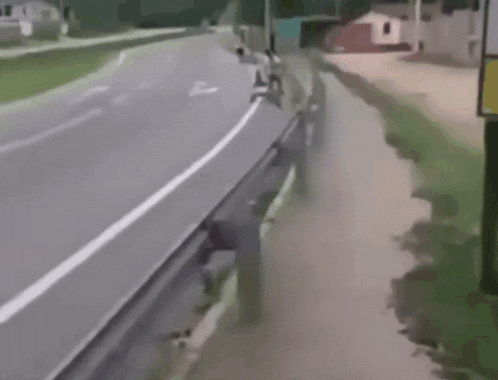 a man is riding a bike down a street while a child is riding a go kart behind him .