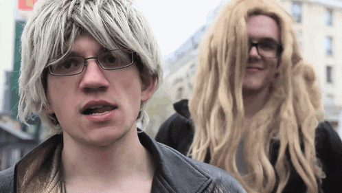 a man with blonde hair and glasses is standing next to another man with long blonde hair
