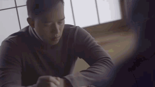 a man sitting at a table with his eyes closed looking at his watch