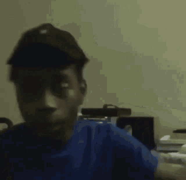 a blurry picture of a person in a blue shirt sitting in a chair .