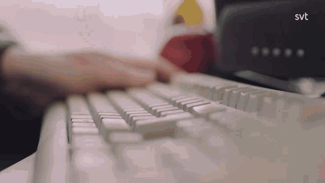 a close up of a person typing on a keyboard with the svt logo visible