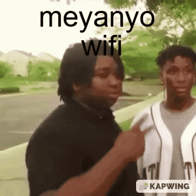 two men are standing next to each other and one of them is pointing at the camera with the words meyanyo wifi above him .